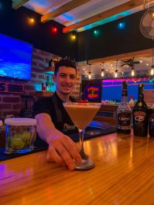 a man sitting at a bar with a martini at Chescos Hotel & Hostel in Salinas