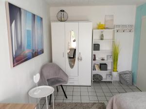1 dormitorio con silla y armario blanco en Ferienhaus Elwetritsche in Landau/Pfalz, en Landau in der Pfalz