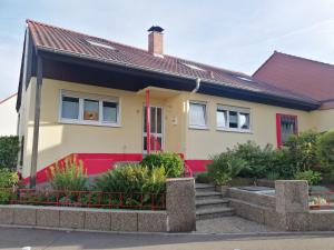 une maison jaune et rouge avec une porte rouge dans l'établissement Ferienhaus Elwetritsche in Landau/Pfalz, à Landau in der Pfalz