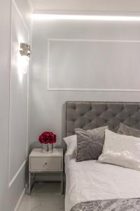 um quarto branco com uma cama com flores numa mesa de cabeceira em Apartament LUNA, Piotrkowska 44 - free parking em Lódź