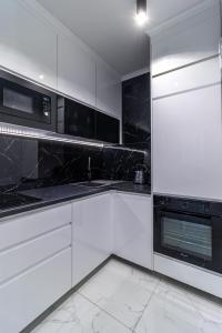 uma cozinha com armários brancos e electrodomésticos pretos em Apartament LUNA, Piotrkowska 44 - free parking em Lódź
