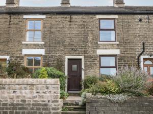 ein Backsteinhaus mit brauner Tür in der Unterkunft Beas Cottage in Highpeak Junction