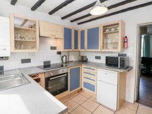 una cocina con armarios azules y blancos y fregadero en Beas Cottage, en Highpeak Junction
