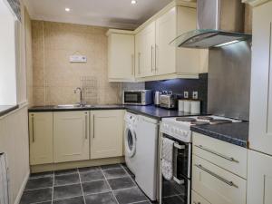 a kitchen with white cabinets and a washer and dryer at Raygill Cottage in Whitby