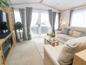 a living room with a couch and a tv at Chantry Lodge in Newquay