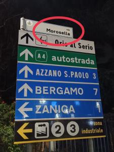 un groupe de panneaux de signalisation sur un poteau dans l'établissement LE MURA Foresteria, à Grassobbio