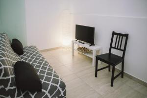 een slaapkamer met een bed, een stoel en een televisie bij Casa Grazia Guest House in Aci Castello