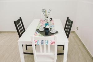 een witte eettafel met drie stoelen en een witte tafel en stoelen suggereren bij Casa Grazia Guest House in Aci Castello