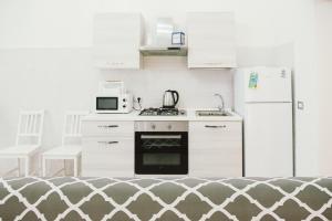 een witte keuken met een fornuis en een koelkast bij Casa Grazia Guest House in Aci Castello