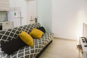 een woonkamer met een bank met gele kussens bij Casa Grazia Guest House in Aci Castello