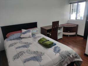 a bedroom with a large bed with a desk and a chair at Zidko Guest House in Ibarra