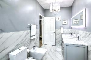 a bathroom with a white toilet and a sink at Sleek Hialeah Home about 20 Mi to Downtown Miami! in Hialeah +24 photos