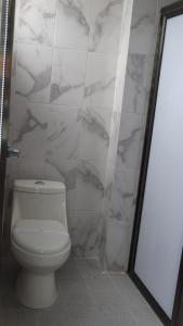 a bathroom with a toilet and a marble wall at MOTEL & HOTEL ALJIBE in Ranchito +6 photos