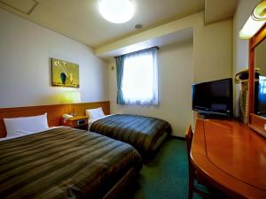 a hotel room with two beds and a flat screen tv at Hotel Route-Inn Shimada Yoshida Inter in Shimada