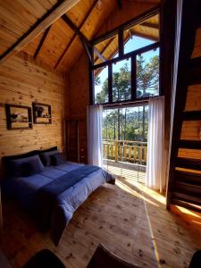 a bedroom with a bed and a large window at Pousada Recanto das Araucárias in Urubici