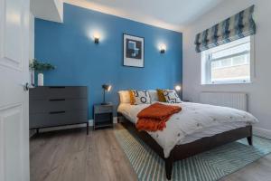 - une chambre avec des murs bleus, un lit et une commode dans l'établissement 2 Bedroom - Tower Bridge - London City by Prime London Stays M-11, à Londres