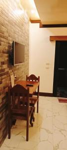 a room with a wooden table and a tv and a chair at Dreamland Nilo Eve Beach Guest Huaz in El Nido