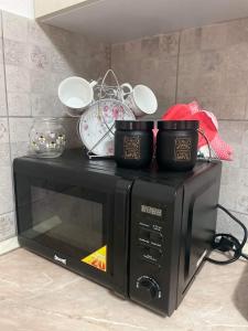 a black microwave with three cups on top of it at Pro arte in Kladovo