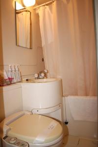 a white bathroom with a toilet and a sink at Business Hotel Nissei in Osaka