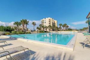 a swimming pool with chairs and a building in the background at Santa Rosa Dunes 1061 in Pensacola Beach