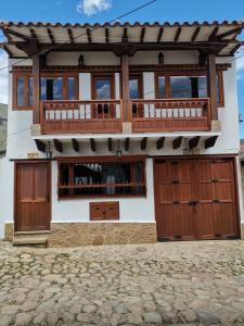 a house with wooden doors and a balcony at Casa ONCE ONCE in Villa de Leyva