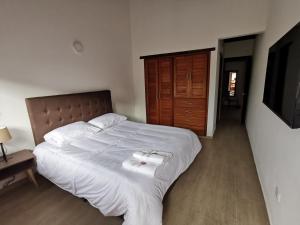 a bedroom with a bed with white sheets and a television at Casa ONCE ONCE in Villa de Leyva
