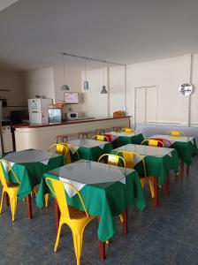 eine Cafeteria mit Tischen und Stühlen sowie grünen und gelben Tischen in der Unterkunft Hotel Lobato in Paysandú