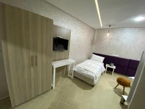 1 dormitorio con 1 cama y TV en la pared en Hôtel Chark, en Guercif