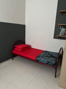 un lit rouge dans un coin de pièce dans l'établissement Qmar Melaka Homestay, à Kampong Kerubong