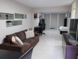 een woonkamer met een bruine bank en een piano bij Studio 4 - ground floor Fremantle apartment in Fremantle