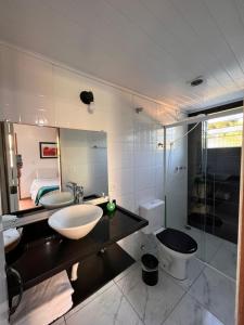 een badkamer met een wastafel, een toilet en een spiegel bij Pousada Araucária Suítes in Campos do Jordão