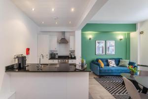 a kitchen and a living room with a blue couch at One Bedroom - Tower Bridge - London City by Prime London Stays M-3 in London