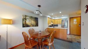 a kitchen and dining room with a wooden table and chairs at Cozy 1BR, steps from Creekside Gondola by Harmony Whistler Vacations in Whistler