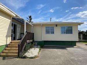 ein Haus mit einer Veranda und einer Holztreppe in der Unterkunft Airport Westney Lodge in Auckland