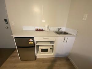 a small kitchen with a sink and a microwave at Airport Westney Lodge in Auckland