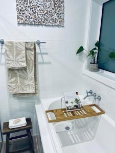 Silver Beach Penthouse في Kurnell: حمام مع حوض استحمام مع كتاب عليه