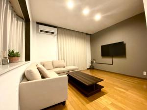 uma sala de estar com um sofá branco e uma televisão de ecrã plano em 外宮前別邸　星凪庵 em Ise