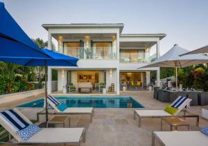 a house with a swimming pool with chairs and umbrellas at Nirvana Barbados by MC Luxury Rentals in Saint James