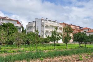 un gran edificio blanco con árboles delante de él en Apartment Seget Donji 10023a, en Trogir