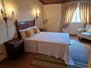 a bedroom with a large bed and a chair at Casinha da Pena - Tomar (Pedreira) in Tomar