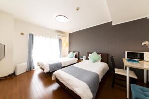 福岡的住宿－機場住宿公寓式酒店，酒店客房设有两张床、一张桌子和一台电视。