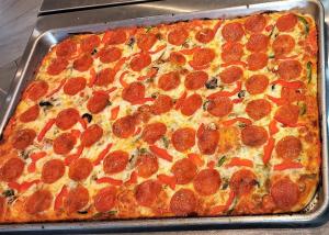 a large pepperoni pizza in a pan on a table at Casa Blanca Inn in Torio
