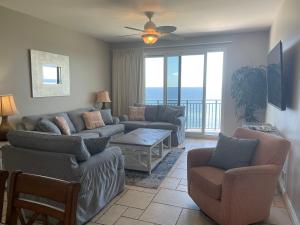 a living room with a couch and chairs and a balcony at Sterling Breeze 1007 in Panama City Beach