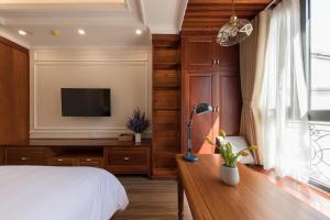1 dormitorio con 1 cama y TV en la pared en Woody House Boutique en Ho Chi Minh