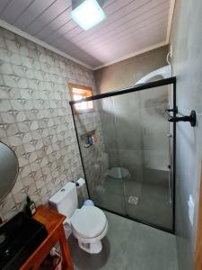 uma casa de banho com um WC e uma cabina de duche em vidro. em Mangue Seco, 120 metros do mar e 100 metros das dunas. em Jaguaruna