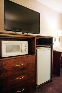 a microwave and a tv on top of a wooden cabinet at Quincy INN and Suites in Quincy