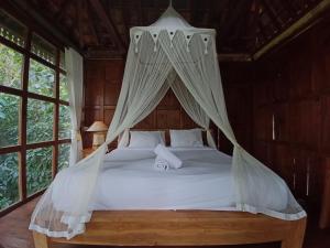 a bedroom with a canopy bed with white sheets and pillows at Bali Jungle Camping by Amerta Experience in Tabanan