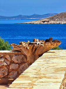 a log laying on top of a stone wall next to the ocean at Villa Aristoteles in Halki