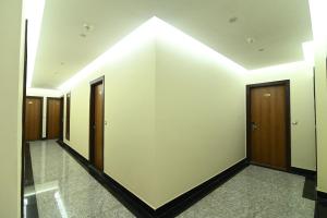 un couloir avec des portes en bois et un mur blanc dans l'établissement The Abhyudyam Ganga, à Haridwar