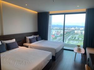 a hotel room with two beds and a large window at Win Condotel Apec Phú Yên in Tuy Hoa